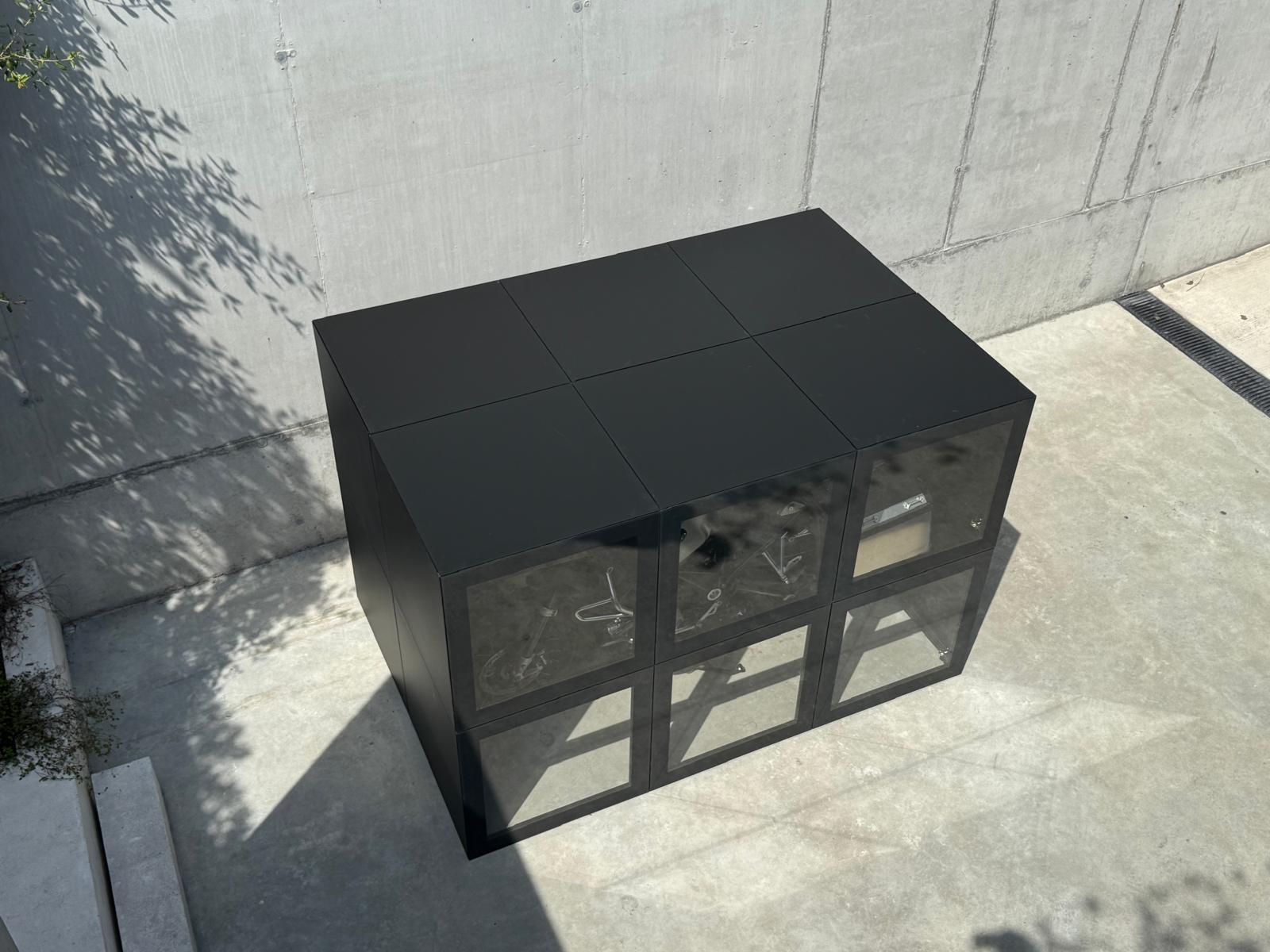 RO. glass-fronted module seen from above · bike stored inside, shadow of an olive tree on the wall